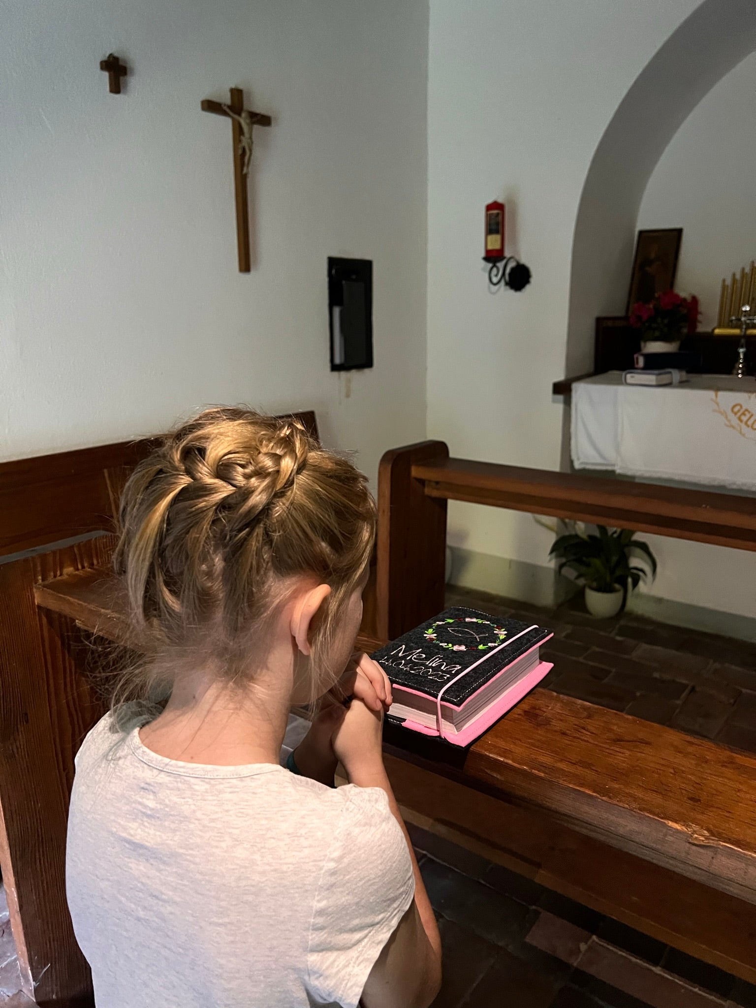 Kind in Kirche beim beten mit Gotteslobhülle