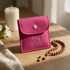 Rosenkranztasche aus pinkem Filz mit Taube auf Holztisch, daneben Holz-Rosenkranz, Kerze und weiße Blumen