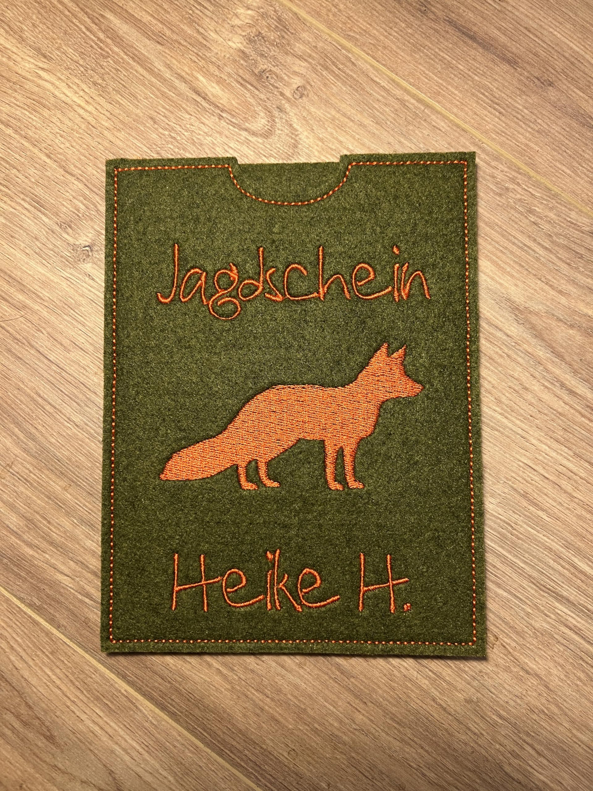 Jagdscheinhülle dunkelgrün mit Fuchs und Name Heike H. auf Holztisch