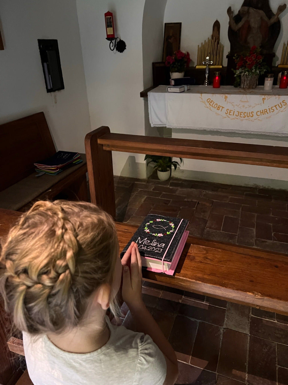 Kind in Kirche mit Gotteslobhülle