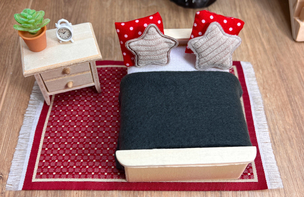 Schlafzimmer für einen Wichtel mit Nachttisch, Bett, Bettdecke, Kissen, Wecker, Teppich und Deko-Pflanze.